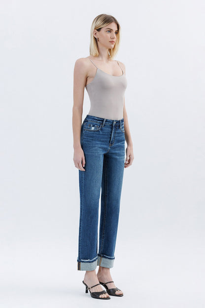 Woman wearing a beige tank top and blue jeans on a white background