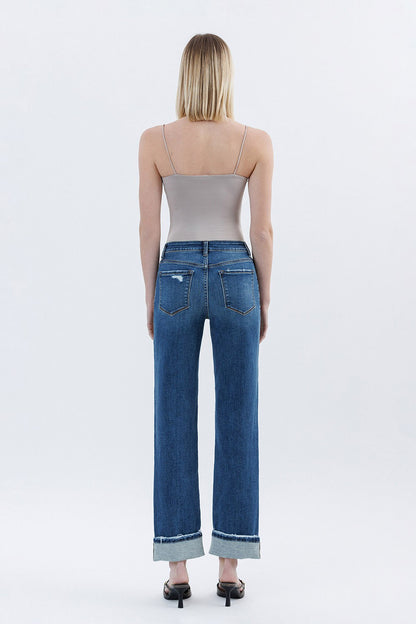 Person wearing blue jeans and a beige top on a white background