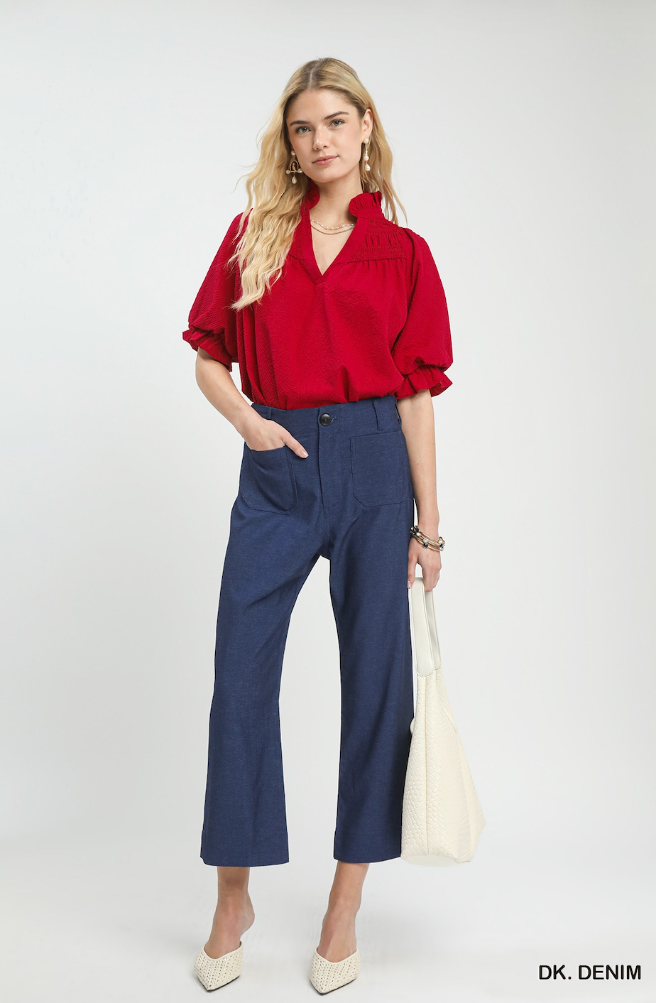 A woman models a red short-sleeve blouse and navy blue cropped wide-leg denim pants, holding a cream woven tote bag. The text 'DK.