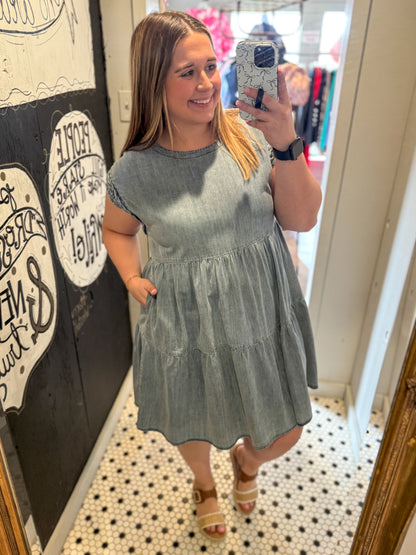 Woman taking a mirror selfie wearing a light blue dress in a store.