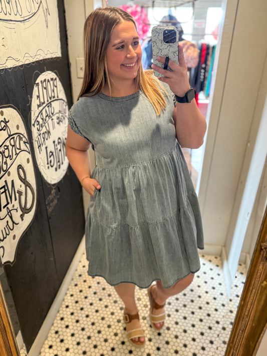 Woman taking a mirror selfie wearing a light blue dress in a store.