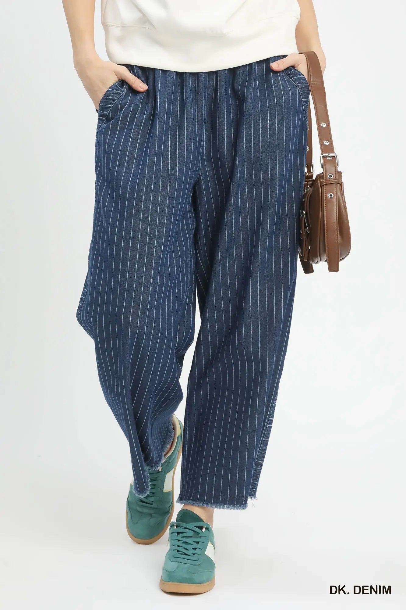 Person wearing blue pinstripe pants with a white top and green shoes on a white background