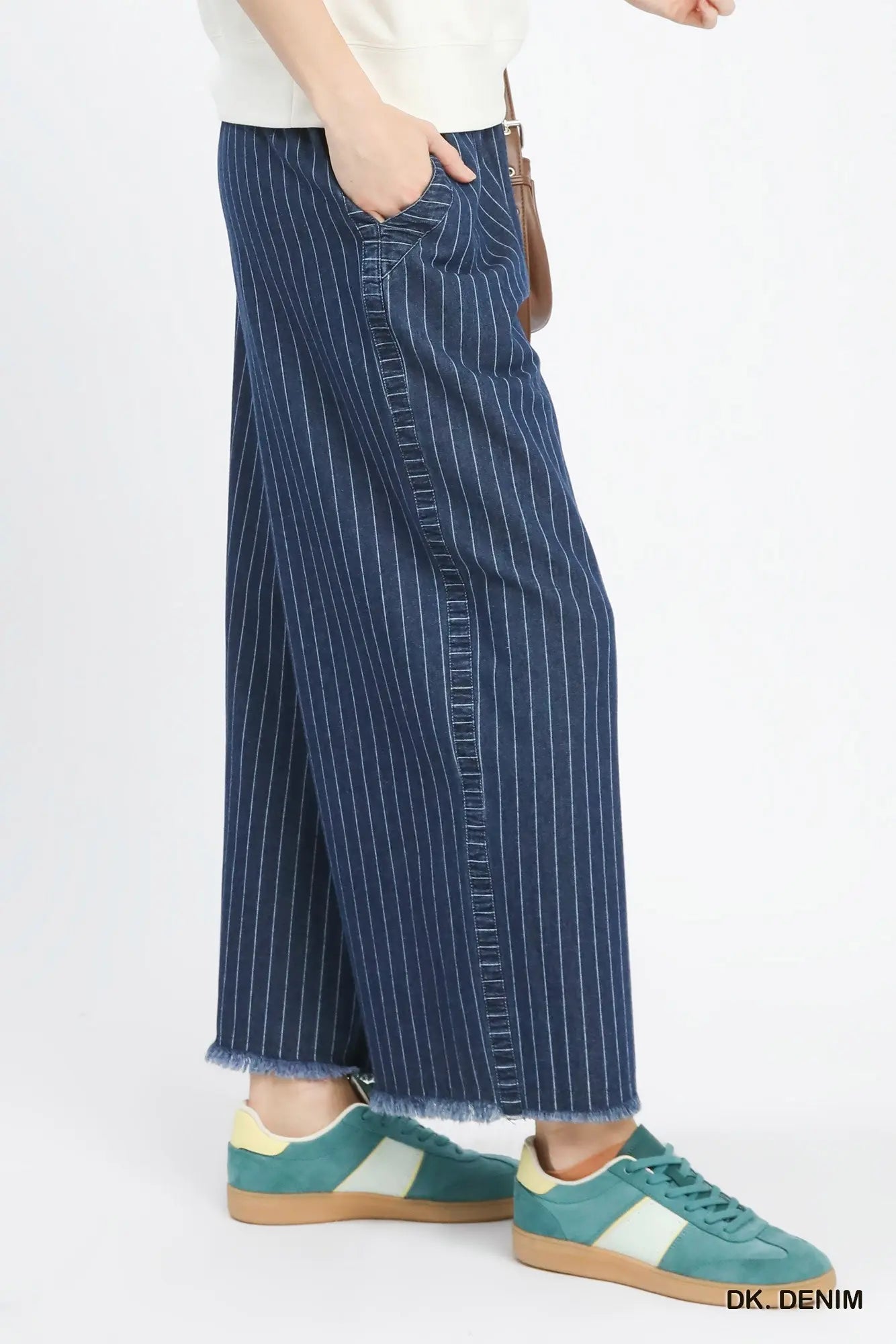 Person wearing blue denim wide-leg pants with a white background