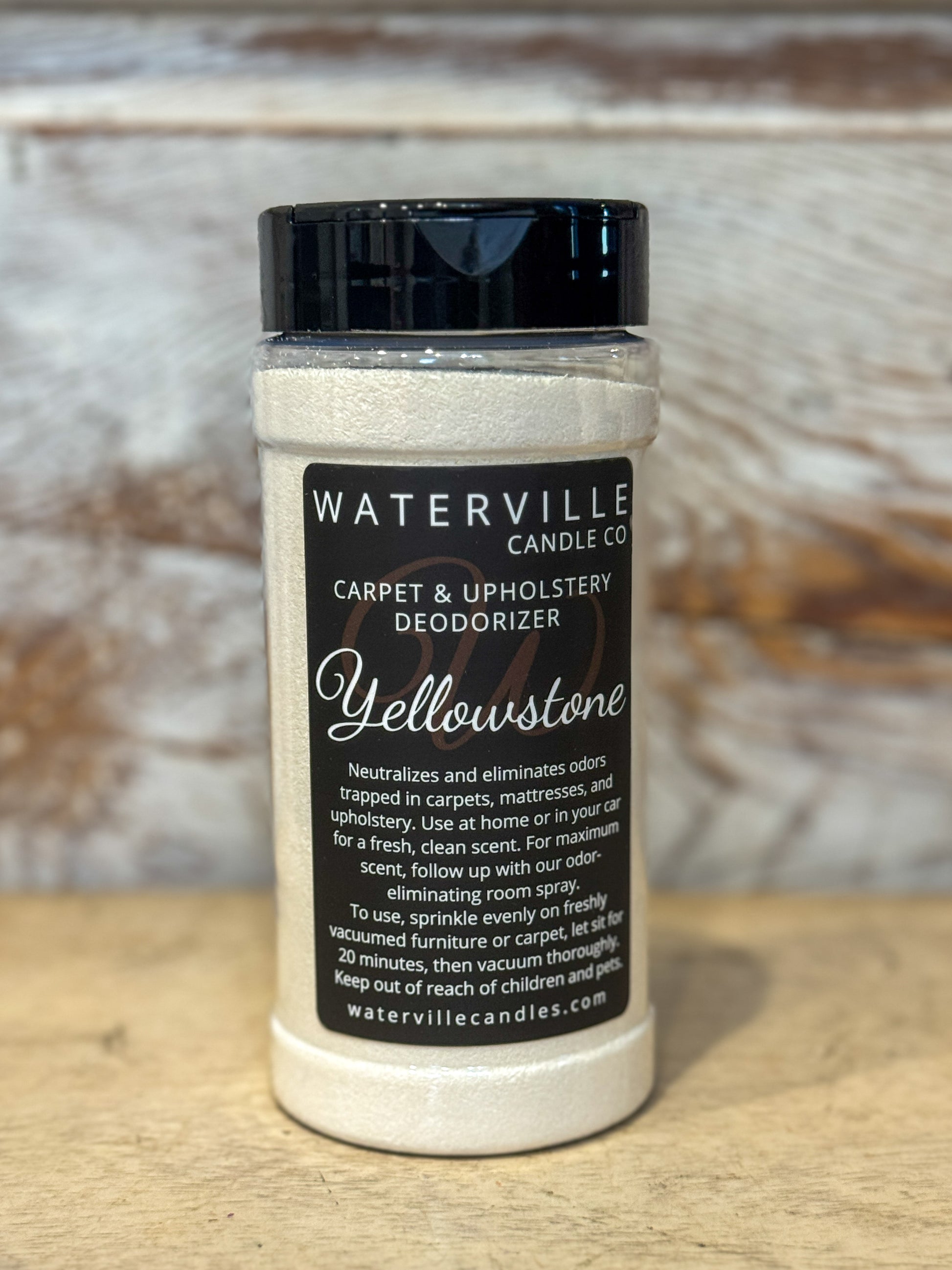 Jar of Waterville Candle Co. carpet and upholstery deodorizer with 'Yellowstone' scent on a wooden surface.